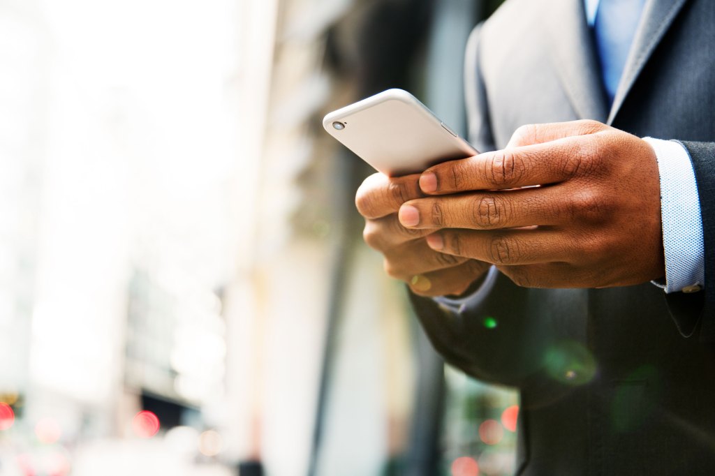 Contact Us: Close up of man using mobile phone