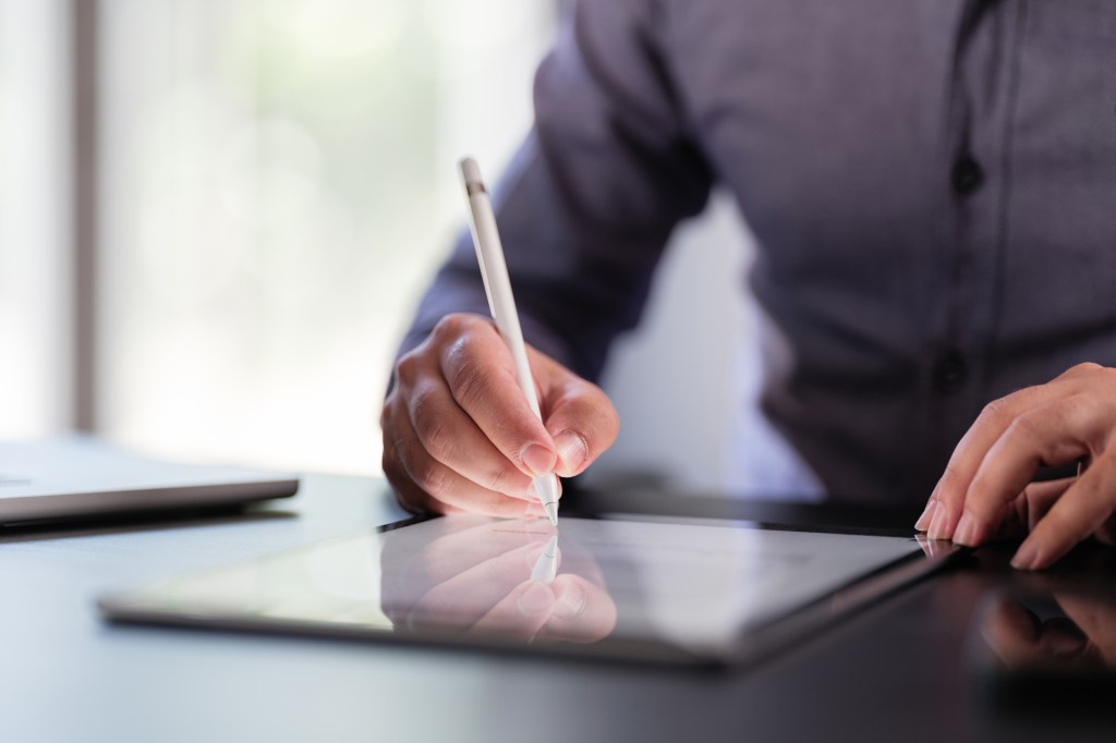 Man signing on digital tablet