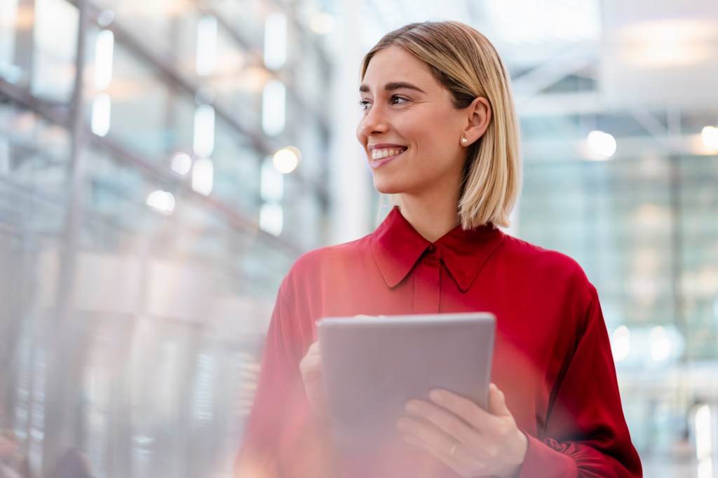 Woman in red shirt holding a tablet in building lobby