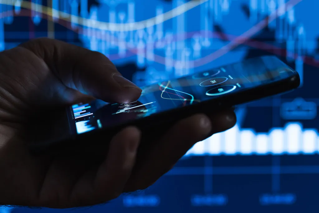 scrolling on a mobile phone, suggesting real-time tracking of outsourced trading